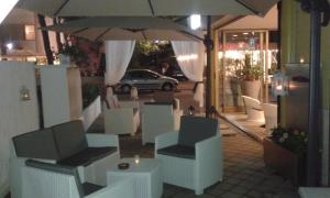 a group of chairs and an umbrella on a sidewalk at Hotel Antonella in Lido di Classe