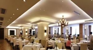 a dining room with white tables and chairs and people at Ambassador Hotel in Shenzhen
