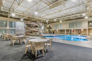 Clarion Hotel & Suites في براندون: مسبح بالطاولات والكراسي وزحليقة