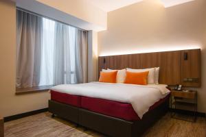 a hotel room with a large bed with orange pillows at Aqueen Prestige Hotel Lavender in Singapore