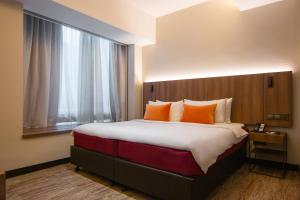 a hotel room with a large bed with orange pillows at Aqueen Prestige Hotel Lavender in Singapore +40 photos