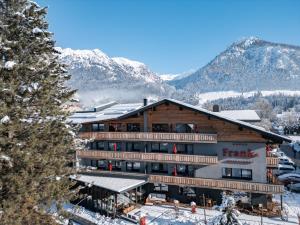 a large building with snow covered mountains in the background at Hotel Franks in Oberstdorf