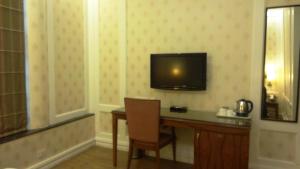 um quarto de hotel com uma secretária e uma televisão na parede em Hotel Bright em Nova Deli