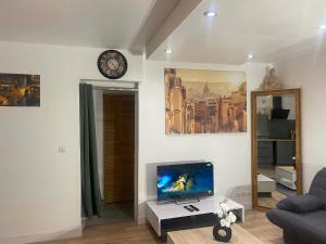a living room with a tv and a clock on the wall at T2 COCOON Centre ville in Marmande