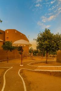 a building with an umbrella next to a dirt road at VVIP GAJBAN Resort in Bikaner