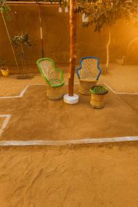 three chairs sitting around a tree in a courtyard at VVIP GAJBAN Resort in Bikaner