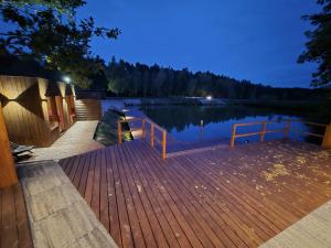 a wooden dock with a wooden railing next to a lake at Łejkówka in Wólka Magierowa