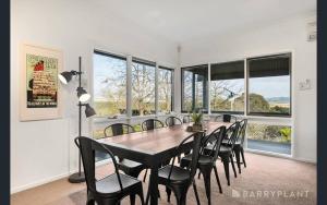 Yarra Valley farmstay - wine views في Tarrawarra: غرفة طعام مع طاولة وكراسي ونوافذ