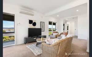 Yarra Valley farmstay - wine views في Tarrawarra: غرفة معيشة مع أريكة وتلفزيون