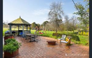 Yarra Valley farmstay - wine views في Tarrawarra: فناء مع شرفة وطاولة وكراسي