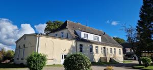 Gutshaus Kletzin mit Pool und Minigolf-Anlage في Siedenbrünzow: منزل أبيض بسقف رمادي