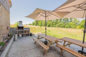 una mesa de picnic con una sombrilla junto a una parrilla en Gîte Petit Talma détente, en Grandpré