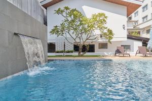 a swimming pool with a waterfall next to a building at Le Charme Vientiane Hotel in Vientiane