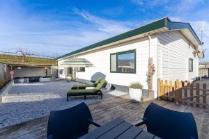 ein Haus mit einer Terrasse mit Stühlen und einem Sonnenschirm in der Unterkunft Welcome in - Vakantiewoning Keetenweg 10 I Met airco en omheinde tuin in Stavenisse