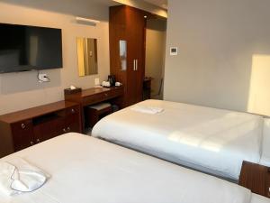 una habitación de hotel con dos camas y un televisor de pantalla plana en EZ HOTEL Kansai Airport Seaside, en Izumisano