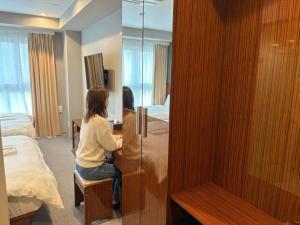 una mujer sentada en un escritorio en una habitación de hotel en EZ HOTEL Kansai Airport Seaside, en Izumisano 170 fotos más