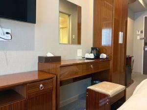 Una habitación de hotel con un escritorio y un espejo. en EZ HOTEL Kansai Airport Seaside, en Izumisano