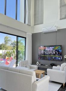 un soggiorno con divani bianchi e una TV di พูลวิลล่าบุรีรัมย์ a Ban Krasang Altre 8 foto