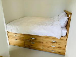 Una cama con sábanas blancas encima de una cómoda de madera. en Beach House Bonna - free parking & bikes, en Scheveningen