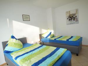 deux lits dans une petite chambre avec des draps bleus et jaunes dans l'établissement Ferienwohnung Monika, à Eching