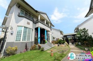a white house with blue doors and a yard at Blue Ocean B&B in Jian