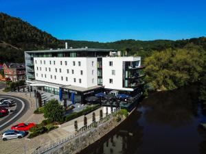 Un edificio blanco al lado de un río al lado de una carretera. en Appart'hotel Urban Lodge, en Chaudfontaine
