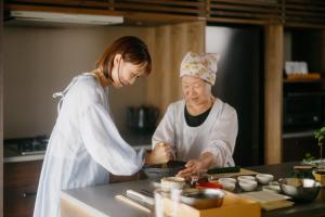 two women standing in a kitchen preparing food at 八百熊川 Yao-Kumagawa in Kumagawa