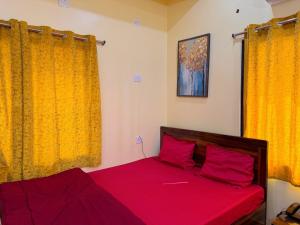 Schlafzimmer mit einem Bett mit roter Bettwäsche und gelben Vorhängen in der Unterkunft Studio 306 Royal Urban in Deoghar