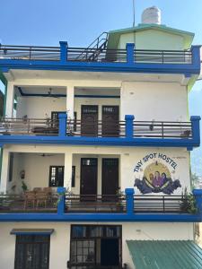 a large white building with blue balconies at Tiny Spot Hostel Rishikesh in Rishīkesh