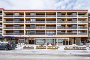 een groot gebouw met een auto ervoor geparkeerd bij Studio Champ Pérouze in La Toussuire