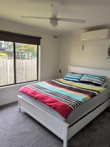 Un dormitorio con una cama con una manta colorida. en Capel Breeze, en Capel Sound