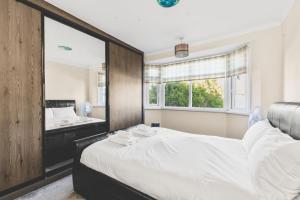 ein Schlafzimmer mit einem großen Bett und einem Spiegel in der Unterkunft Spacious 4BDR House with Parking by Heathrow in Hillingdon