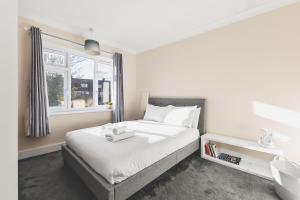 ein Schlafzimmer mit einem weißen Bett und einem Fenster in der Unterkunft Spacious 4BDR House with Parking by Heathrow in Hillingdon