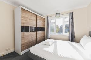 ein Schlafzimmer mit einem großen weißen Bett und einem Fenster in der Unterkunft Spacious 4BDR House with Parking by Heathrow in Hillingdon