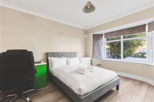 ein Schlafzimmer mit Bett, Schreibtisch und Fernseher in der Unterkunft Spacious 4BDR House with Parking by Heathrow in Hillingdon