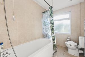 ein Badezimmer mit Badewanne und Toilette in der Unterkunft Spacious 4BDR House with Parking by Heathrow in Hillingdon + 28 Fotos