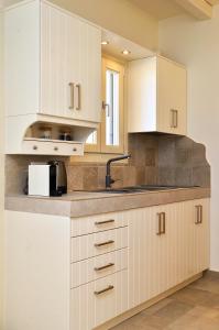 a kitchen with white cabinets and a sink at Sohoro in Koufonisia