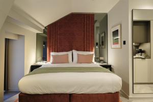 a bedroom with a large bed with pink pillows at The Wellington Glasgow by Adina in Glasgow