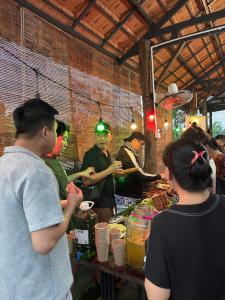 a group of people standing around a table with food at Tổ Homestay in Tân Phú +33 photos