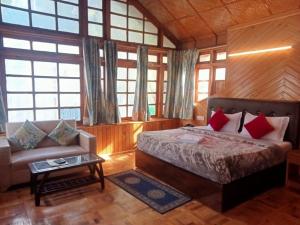 Melody Orchard Cottage Manali في Jagatsukh: غرفة نوم بسرير واريكة ونوافذ