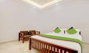a bedroom with a large bed and a chair at PALM GROVE By D2V in Cochin