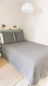 a bed in a bedroom with a white wall at cocon des arènes et parking in Nîmes