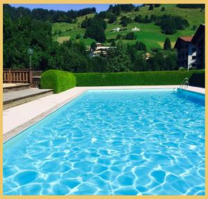 ein großer blauer Pool mit einem Hügel im Hintergrund in der Unterkunft Le Cocon Alpin I Megève in Megève