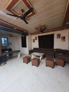 ein Wohnzimmer mit einer Couch und einem Deckenventilator in der Unterkunft Zenzi Stays 11 BHK With 2 Pools in Khandāla