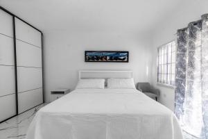 a white bedroom with a white bed and a picture on the wall at Hibiscus Charm in Red Hills +60 photos