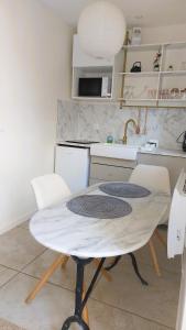 a kitchen with a white table with chairs and a sink at cocon des arènes et parking in Nîmes