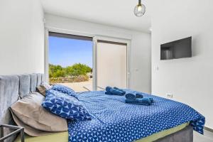a bedroom with a bed with blue sheets and a window at Villa Karolina by Villa Plus in Štokovci