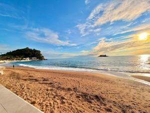 a beach with a bench on the sand and the ocean at Beachfront Apartments Oaza in Petrovac na Moru