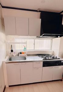 a white kitchen with a sink and a stove at HYGGE HOUSE Tabibitonoie - Vacation STAY 33409v in Kashiwa +2 photos