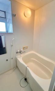 a bath tub in a bathroom with a light on the wall at HYGGE HOUSE Tabibitonoie - Vacation STAY 61173v in Kashiwa